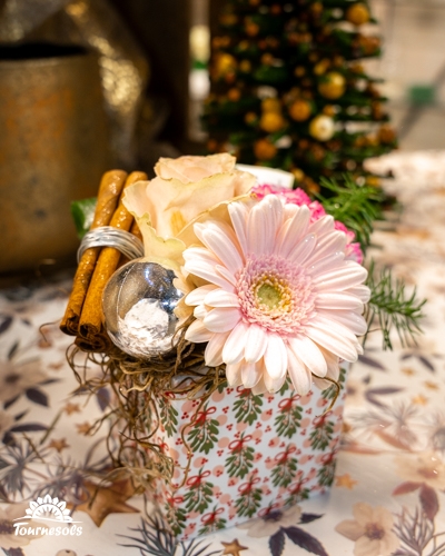 Composition florale de Noël avec gerbera et roses dans un vase décoré.